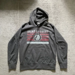 Saint laurent hoodie - Säljer en fet snygg hoodie från Saint Laurent i väldigt bra skick och är köpt nypris 5000 och därför då säljer för 2000! Det står att de e storlek M men den passar S och om man är 170cm och den är väldigt skön och passar riktigt bra nu till hösten/våren! Hör av dig vid pris vid snabb affär och funderingar!