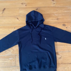 Mörkblå hoodie från Polo Ralph Lauren - Snygg mörkblå hoodie från Polo Ralph Lauren med klassisk broderad logga på bröstet. Tröjan är helt ny och aldrig använd då den är för liten.
