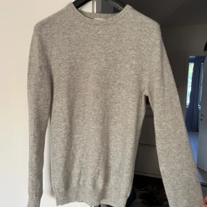 Grå kashmirtröja från John Henric - Supermjuk och stilren grå tröja i 100% kashmir från John Henric. Klassisk rund halsringning och långa ärmar, perfekt för lager-på-lager. Enkel design som funkar till allt och känns lyxig mot huden.