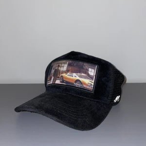 Svart Maggiore keps limited edition - Limited edition svart keps från Maggiore med mesh på baksidan och justerbart spänne. Framsidan har en patch med bilmotiv och texten 'MAGGIORE'. Kepsen levereras med originalbox och dustbag. Perfekt för dig som gillar unika accessoarer.