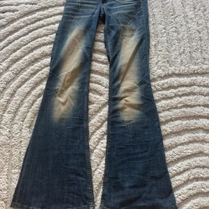 Blå bootcut jeans från Cheap Monday - Snygga blå bootcut jeans från Cheap Monday med slitna detaljer och ljusa partier framtill och baktill. Klassisk femficksmodell, låg midja och coolt Cheap Monday-märke bak. Perfekta för dig som gillar retrovibbar och breda ben. Har även bara använt 2 gånger.