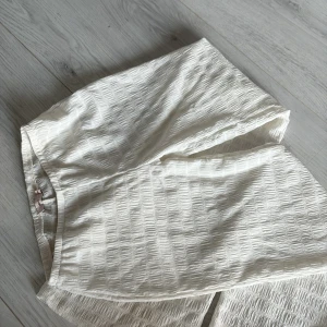 Byxor  - Snygga byxor  med strukturerat tyg och diskret rutmönster. Byxorna  har en rak passform och resår i midjan för extra komfort. Perfekt för dig som gillar stilrena och trendiga plagg.