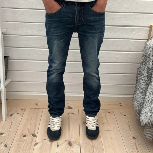 Blå jeans slim/straght fit - Säljer ett par blå slim fit jeans  med snygg tvätt och klassiska kontrastsömmar. Jeansen har rak passform, fem fickor och subtila slitningar för en cool look. Perfekta för en avslappnad stil.