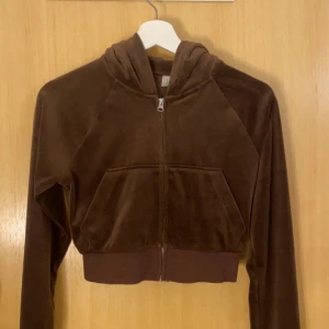 Brun croppad kofta med luva i storlek XS - Mysig brun croppad kofta med luva från H&M i storlek Xs som har en dragkedja framtill. Har stora fickor på magen och bred mudd nedtill. Perfekt för dig som gillar en chill och trendig stil. Den är använd max 3 gånger! Den är stretchig så den passar även en som har storlek S/M. Köparen står alltid för frakten❤️
