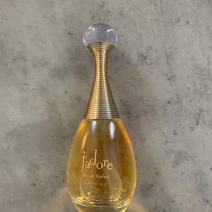 J'adore Eau de Parfum 100ml Dior - J'adore Eau de Parfum från Dior i en elegant droppformad glasflaska med guldfärgad hals och rund, transparent kork. Parfymen är gyllengul och flaskan rymmer 100 ml. En ikonisk och lyxig doft som verkligen sticker ut i badrumshyllan.‼️‼️det finns ingen kartong ‼️‼️
