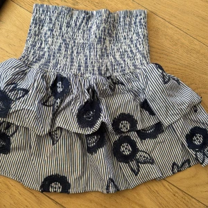 Randig volangkjol med broderade blommor - Supersöt kortkjol med blåvita ränder och mörkblå broderade blommor. Storlek S, från Lindex 