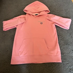 Rosa hoodie från GANT med huva - NYPRIS: 799kr Säljer en snygg rosa hoodie från GANT med klassisk logga på bröstet. PRISET GÅR ATT DISKUTERAS💕 Tröjan har huva, känguruficka och ribbade muddar. Perfekt för dig som gillar en avslappnad och trendig stil. Mjuk bomullskvalitet och normal passform.