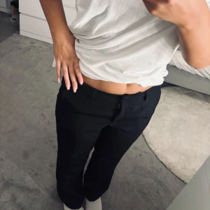 Svarta kostymbyxor från Nelly - Snygga svarta kostymbyxor från Nelly med klassisk rak passform och midwaist. Byxorna har pressveck, bälteshällor och diskreta fickor både fram och bak. Perfekta för en clean och stilren look, passar till både sneakers och boots.