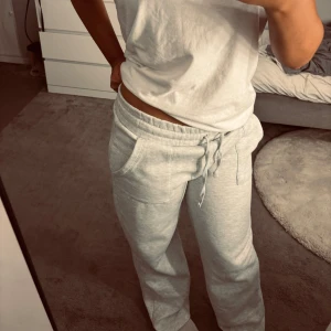 Grå mjukisbyxor från lager 157, storlek M - Säljer ett par ljusgrå mjukisbyxor från lager 157 i storlek M. Byxorna har bred resår i midjan med snörning, raka ben och två stora fickor fram. Sköna och chill, perfekta för att hänga hemma eller dra till gymmet. Materialet är mjukt och känns som bomull.