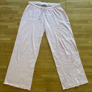 Ljusrosa mjukisbyxor från Lager 157 - Supermysiga ljusrosa mjukisbyxor från Lager 157 med breda ben och elastisk midja med snörning (ser ljusare ut på bilden). Materialet är ribbat och har en skön, mjuk känsla. Perfekta för chill dagar hemma eller när du vill vara extra comfy. Snygg volangkant längst ner på benen för en extra touch. Köpte nyligen på Plick men var tyvärr för korta så nu säljer jag dem vidare. 