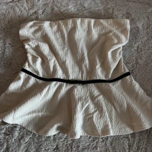  Tubtopp Holly & White  - Säljer en krämvit bandeau tubtopp från Holly & Whyte by Lindex i storlek M men passar mig som har XS/SToppen har svart band med en liten rosett. Aldrig använd och finns ej att köpa!