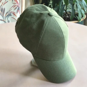 Grön keps från Lindex i linne - Snygg grön keps från Lindex i linne med klassisk böjd skärm och justerbar rem med metallspänne baktill. Perfekt för dig som vill ha en enkel och stilren look. Kepsen har en mjuk och lätt känsla som passar bra till varma dagar.