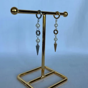 Asymmetriska örhängen med pärlor och spikes - Snygga örhängen med en mix av silver och guld. Varje örhänge har två vita pärlor, en metallring och en konformad spike i metall. Ena örhänget är i silverton och det andra i guldfärg, vilket ger en cool, asymmetrisk look.