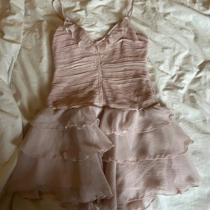 Ljusrosa volangklänning från H&M  - Supersöt ljusrosa kortklänning från H&M med tunna axelband och v-ringad hals. Klänningen har flera lager med volanger. Skriv om ni har några frågor!💞