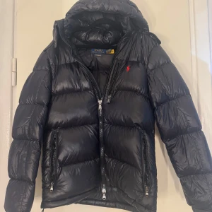 Svart vinterjacka från Polo Ralph Lauren - Säljer min Ralph Lauren jacka för att de inte kommer till användning, den kommer med kvitto och tags. Det är killversionen men jag som tjej använde den, det är strlk XS men passar mig som egentligen har M. ORGINALPRIS: 6100kr