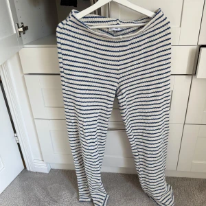 Randiga stickade byxor från MNG - Säljer ett par stickade byxor från MNG i storlek L. Byxorna har ett snyggt randigt mönster i blått och vitt, med en mjuk och grovstickad känsla. 