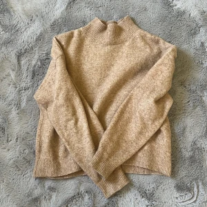 Beige stickad polotröja från H&M - Säljer en beige stickad polotröja från H&M i storlek S. Tröjan har en hög ribbad krage och långa ärmar med ribbade muddar. Perfekt för dig som gillar en enkel och clean look med lite oversized känsla. Supermjuk och skön att ha på sig under kyliga dagar.
