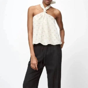Vit omlott halterneck topp från Zara - Supersnygg vit halterneck topp från Zara med omlottknytning i nacken. Toppen har ett mönster i beige och silver. Luftig passform och perfekt för sommar men funkar alltid. Materialet känns lätt och skönt mot huden!💞💞