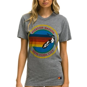 Grå t-shirt Aviator Nation NYC - Snygg grå t-shirt från Aviator Nation med färgglatt tryck på bröstet där det står 'Aviator Nation New York City' och en surfare. Liten broderad logga nertill. Skön och mjuk bomullskänsla, perfekt till chill dagar.