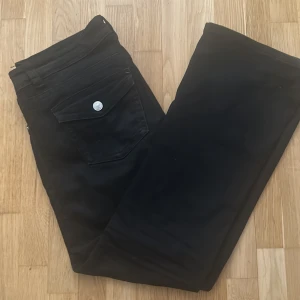 Svarta jeans från Ginatricot - Svarta bootcut jeans från Gina i storlek 42. Modellen har klassisk design med två bakfickor med lock och silverfärgade knappar. Perfect för dig som gillar Stockholm stil 
