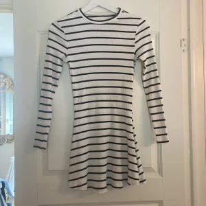 Randig vit och svart klänning Primark - Supersnygg kortklänning från Primark med svartvita horisontella ränder. Klänningen har lång ärm, rund hals och är gjord i mjuk ribbad bomull som sitter skönt mot kroppen. Perfekt för dig som gillar enkel och stilren look med lite edge.