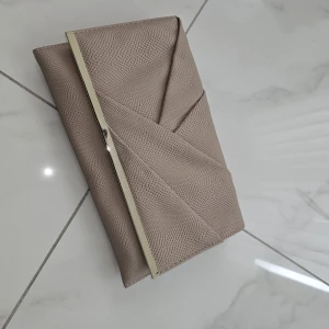 Beige kuvertväska med guld-detalj - Snygg beige kuvertväska med strukturerad yta och elegant guld-detalj längs kanten. Stilren design med geometriska linjer som ger en modern vibe. Perfekt storlek för mobilen och det viktigaste. Passar dig som gillar minimalistisk stil.