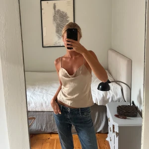 Festtopp - Säljer en champagnefärgad festtopp från Zara med justerbara smala axelband och snygga knappar i ryggen. 