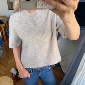 Beige stickad tröja i alpacka ull från Gina Tricot - Säljer en beige stickad tröja från Gina Tricot i storlek S, Gina tricot premium quality i alpacka ull blandning. Tröjan har korta ärmar, rund hals och en loose passform som ger en chill vibe. Materialet är mjukt och skönt, perfekt för lager-på-lager under hösten eller våren. Enkel och stilren design som funkar till jeans eller kjol. Skick på bilderna
