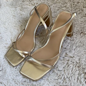 Guldiga sandaler med klack från H&M - Säljer ett par guldiga sandaler från H&M med fyrkantig tå och höga blockklackar.💛Passar mig som har 37-38.