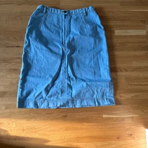 Ljusblå jeanskjol Prêt à Porter - Säljer en ljusblå lång jeanskjol från Prêt à Porter i storlek 36. Kjolen har klassisk midja med hällor, knapp och dragkedja framtill. Snygg rak passform och stilren design som är enkel att matcha med olika toppar.