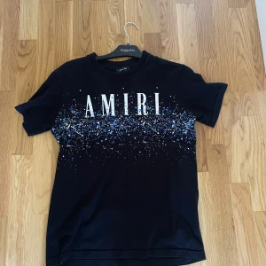 Svart AMIRI t-shirt med blått stänkmönster - Amiri t Shirt i helt nytt skick inga tecken på användning. Qr kod inuti tröjan finns.