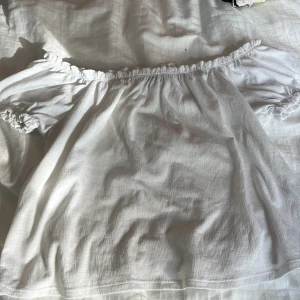 Vit offshoulder blus från Gina Tricot - Superfin vit blus från Gina Tricot i storlek M. Modellen är offshoulder med volangkant upptill och elastiska detaljer vid ärmslut. Luftigt tyg i bomull. Passar som S också!