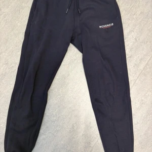 Mörkblå mjukisbyxor från McKenzie - Mörkblå mjukisbyxor från McKenzie. Mjukt bomullsmaterial med fleece på insidan. Passformen är loose och de har ribbade muddar vid bensluten för extra komfort.