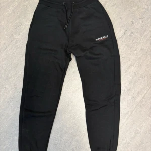 Svarta mjukisbyxor från McKenzie - Svarta mjukisbyxor från McKenzie med logga på vänster lår. Sköna och avslappnade med loose passform, perfekta för chill eller träning. Tillverkade i mjukt bomullsmaterial.
