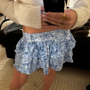 Blåvit volangkjol med blommigt mönster - Supersöt kort kjol i blått och vitt med blommigt mönster och volanger. Kjolen är från Gina tricot och är helt oanvänd💓