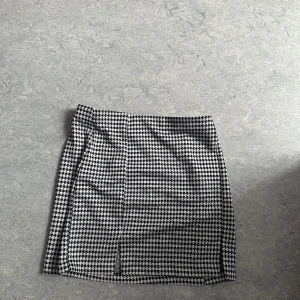 Rutig kortkjol från H&M Divided - Oanvänd. Skickar iväg samma dag eller dagen efter🙌🏼Snygg svartvit rutig kortkjol från H&M Divided i storlek S. Kjolen har klassiskt hundtandsmönster, liten slits framtill och är gjord i mjuk polyesterblandning. Perfekt att styla med boots eller sneakers för en trendig look.