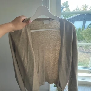 Beige kofta från VILA - Säljer en stilren beige kofta från VILA med öppen front och långärmad design. Koftan är i storlek xl men passar mig som brukar ha s i koftor