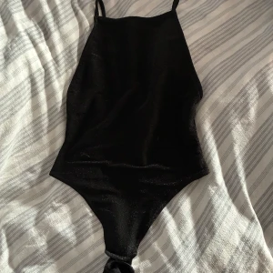 Svart glittrig body - Snygg svart body med glittrigt tyg 