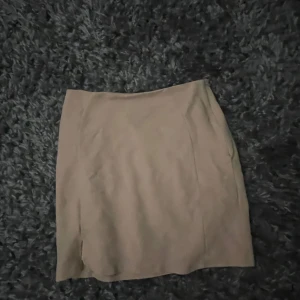 Beige kortkjol från Bik Bok - Säljer en stilren beige kortkjol från Bik Bok i enkel design. Kjolen har en rak passform och är perfekt att matcha med både sneakers och boots. Materialet känns mjukt och lätt, vilket gör den skön att bära under varmare dagar.