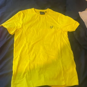 Två färgstarka Lyle & Scott t-shirts - Säljer två snygga t-shirts från Lyle & Scott, en i knallgul och en i stark rosa. Båda har klassisk passform, rund hals och den ikoniska fågel-loggan broderad på bröstet. Perfekta för dig som vill sticka ut med färg! Materialet är mjuk bomull som känns skönt mot huden.