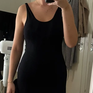 Svart ribbad klänning från H&M - Säljer en svart ribbad klänning från H&M i storlek S. Klänningen är figurnära med ärmlös design och rundad halsringning. Perfekt för dig som gillar enkel och stilren look. Materialet är mjukt och stretchigt, vilket gör den superbekväm att bära. Säljer då den ej blir använd.