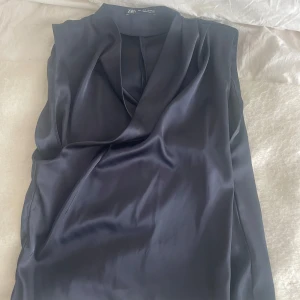 Blus från Zara  - Snygg marinblå  blus från Zara i satin material. Ärmlös design som ger en clean och modern look, perfekt för att dressa upp outfiten. Blusen har en elegant omlott-detalj framtill och känns lyxig tack vare sitt silkesliknande tyg❤️