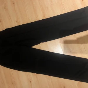 Svarta kostymbyxor från NA-KD - Snygga svarta kostymbyxor från NA-KD i klassisk rak modell. Byxorna har pressveck längs benen och är perfekta för en clean och stilren look. Tillverkade i ett mjukt material som sitter skönt hela dagen.