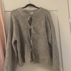 Grå stickad kofta med knyt från Gina Tricot - Mysig grå stickad tröja med rosetter i fram  i storlek 170 från Gina young skriv om du undrar nåt 💗