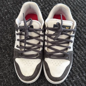 DC Shoes sneakers i mocka och skinn - Snygga DC Shoes sneakers i svart och vitt med klassisk logga på sidan. Skorna har ovandel i mocka och skinn, platt sula och rund tå. Perfekta för dig som gillar streetwear och skate-stil. Skön passform och cool kontrast mellan färgerna.