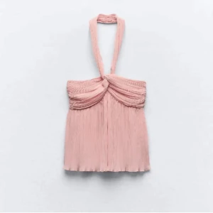 Plisserad rosa halterneck topp - Säljer en superfin ljusrosa halterneck topp med plisserat tyg och snygg twistad detalj framtill. Toppen har en luftig och flowy passform, perfekt för varma dagar. 