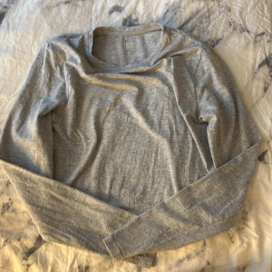 Grå tunn långärmad tröja från lager 157 - En enkel och skön grå tunn långärmad tröja från lager 157. Perfekt för chill dagar eller när du vill ha något basic och bekvämt. Tröjan har rund hals och är gjord i mjuk bomull som känns nice mot huden.