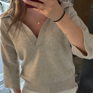 Beige stickad kofta från H&M - Säljer en beige stickad kofta från H&M med bred krage och v-ringad hals. Tröjan har trekvartsärm och ribbade muddar vid ärmslut och nederkant. Väldigt slapp och bekväm men samtidigt stilig och snygg!💞