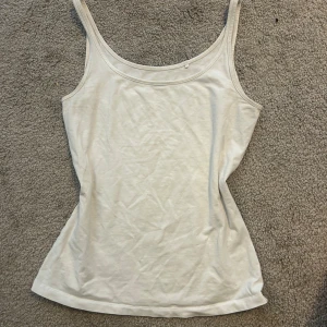 Vit linnetopp  - Enkel och stilren vit linnetopp från Lindex. Toppen har smala axelband och rundad halsringning, perfekt för lager-på-lager eller sommarens varma dagar. Storlek xs men passar nog s också. 