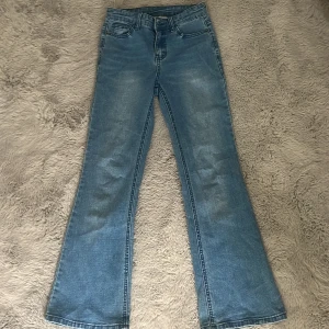 Blå bootcut jeans från UNIQ, stl 146 - Snygga ljusblå bootcut jeans från UNIQ Denim Wear i storlek 146. Klassisk femficksmodell med normal passform och utsvängda ben. Jeansen har justerbar midja och är tillverkade i mjukt denimtyg som är skönt att bära hela dagen.